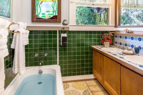 a green tiled bathroom with a tub and two sinks at Volcano Village Estates in Volcano
