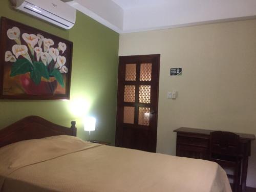 - une chambre avec un lit et un tableau de fleurs dans l'établissement Hotel Vizcaíno León, à León