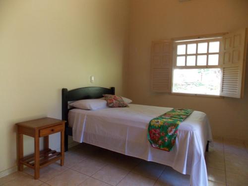 Schlafzimmer mit einem Bett mit einem Tisch und einem Fenster in der Unterkunft Águas Vivas Hotel Fazenda in Pirenópolis
