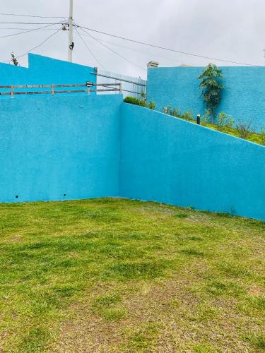 a blue wall next to a field of grass at SÍTIO MARAVILHOSO EM MAIRIPORÃ opção de 1 quarto para 8 pessoas ou 4 quartos acima de 9 pessoas in Mairiporã
