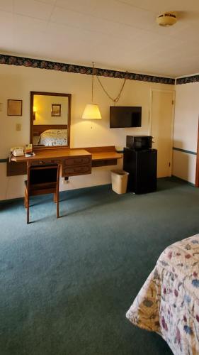 a hotel room with a bed and a desk and a bed at Robin Hood Motel in Raton