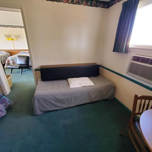 a small bedroom with a bed and a window at Robin Hood Motel in Raton