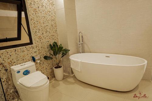 a bathroom with a white tub and a toilet at Bông Villa Hotel & Apartment in Kon Tum