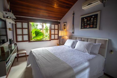 a bedroom with a white bed and a window at Búzios House Oficial in Búzios