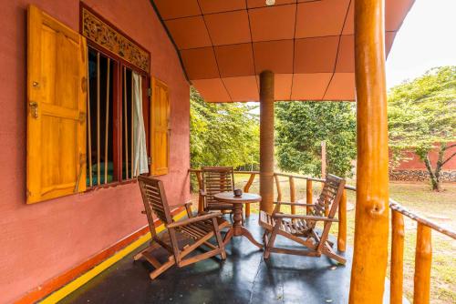 a porch with chairs and a table and a window at Yala Peace Cottages in Tissamaharama