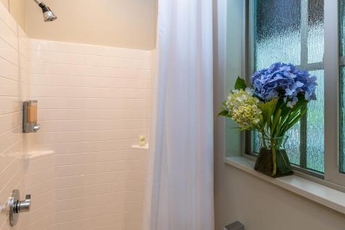 a bathroom with a vase of blue flowers in a window at Volcano Village Estates in Volcano