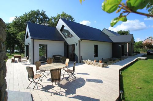 une terrasse avec une table et des chaises ainsi qu'une maison dans l'établissement La Balade des Marais, à Saint-Molf