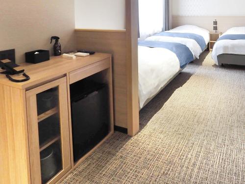 a bedroom with two beds and a dresser with a mirror at Hotel Abest Grande Takatsuki in Takatuki