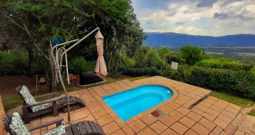 a swimming pool with an umbrella on a brick patio at Shamba Yetu Mountain Lodge in Maanhaarrand