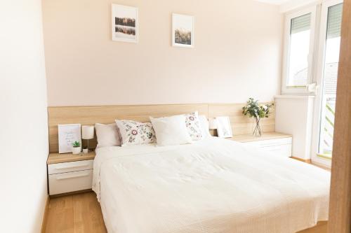 a white bedroom with a white bed and two windows at Vigorous Bled Apartment in Bled