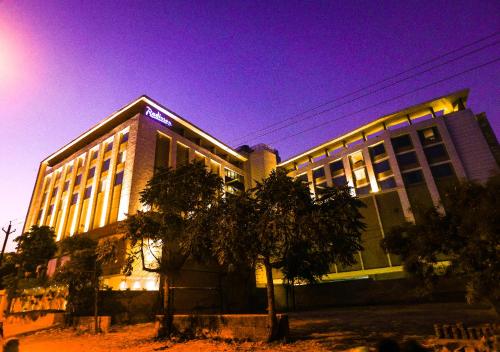 a large building with a tree in front of it at Radisson Bhopal in Bhopal