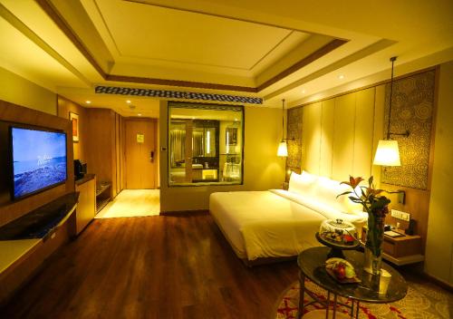 a hotel room with a bed and a flat screen tv at Radisson Bhopal in Bhopal