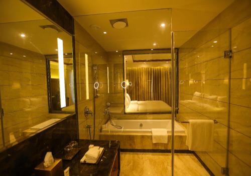 a bathroom with a shower and a tub and a sink at Radisson Bhopal in Bhopal