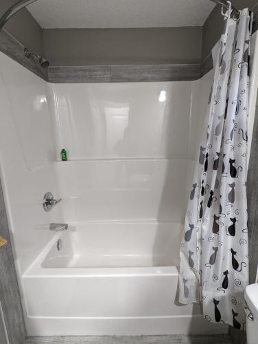 a white bath tub in a bathroom with a shower curtain at Riverside Motel & Suites in Medicine Hat