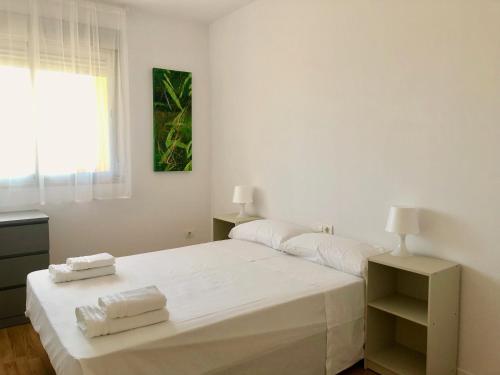 een witte slaapkamer met een bed en een raam bij Luminoso Apartamento a 10 minutos de Granada con Piscina in Alhendín