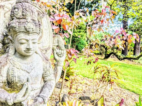 a statue in a garden with flowers and trees at Kehena Mauka Nui Club LGBTQIA+ Clothing Optional in Pahoa
