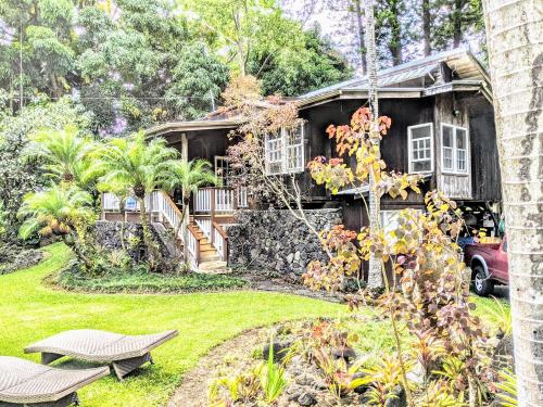 a house with a stone facade and a yard at Kehena Mauka Nui Club LGBTQIA+ Clothing Optional in Pahoa