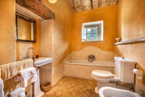 a bathroom with a toilet and a tub and a sink at Lavacchio 10 by Salogi Villas in Montalcino