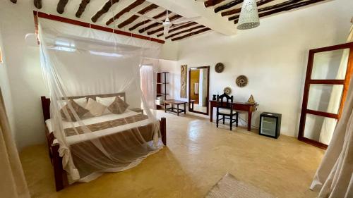 a bedroom with a bed and a desk in a room at Atii Garden Bungalows in Nungwi