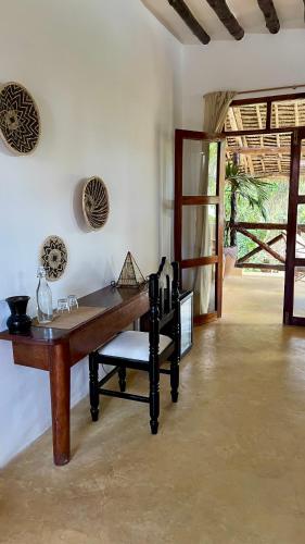 a dining room with a wooden table and a chair at Atii Garden Bungalows in Nungwi