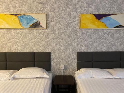 two beds sitting next to each other in a bedroom at Hotel SMZ Sungai Siput (u) in Kampong Rimba Panjang
