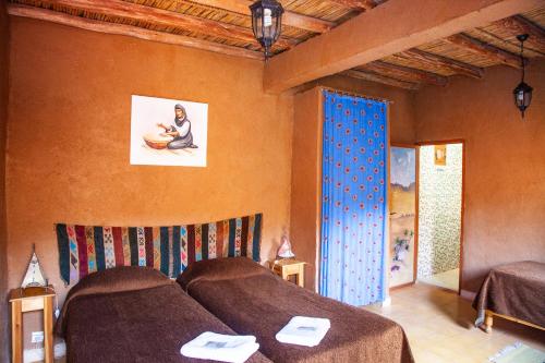 a bedroom with two beds and a painting on the wall at La Maison de l'Homme Bleu in Tighmert