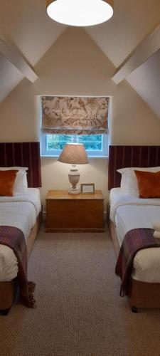 a bedroom with two beds and a lamp on a table at The Colesbourne Inn in Colesbourne