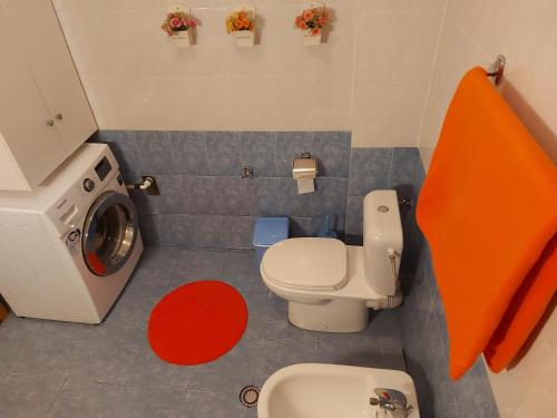 a small bathroom with a toilet and a washing machine at Geni Apartment in Korçë
