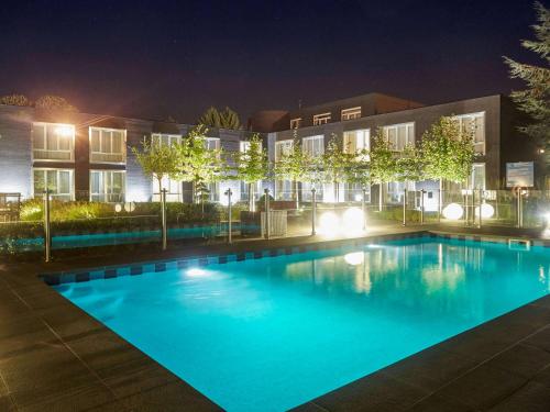 - une piscine en face d'un bâtiment la nuit dans l'établissement Novotel Lens Noyelles, à Noyelles-Godault