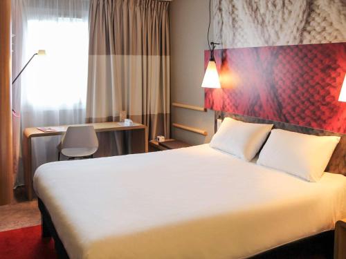una camera d'albergo con un grande letto e una scrivania di ibis Arcachon la Teste de Buch a La Teste-de-Buch