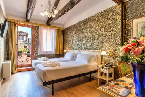 a bedroom with a large bed and a table at Hotel La Fenice et Des Artistes in Venice