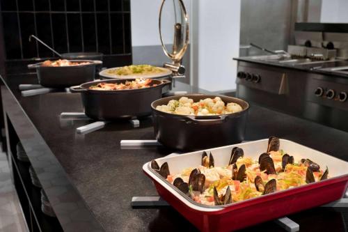 a kitchen with several pans of food on a counter at Hotel Dolce La Hulpe Brussels in La Hulpe