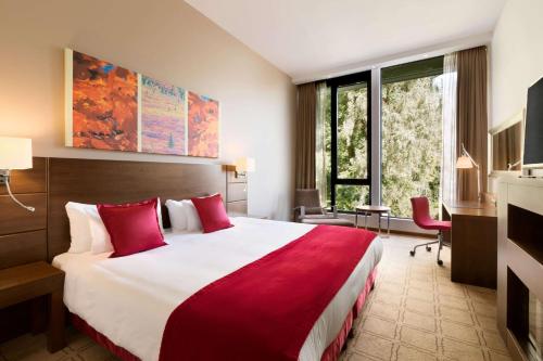 a hotel room with a large bed with red pillows at Hotel Dolce La Hulpe Brussels in La Hulpe