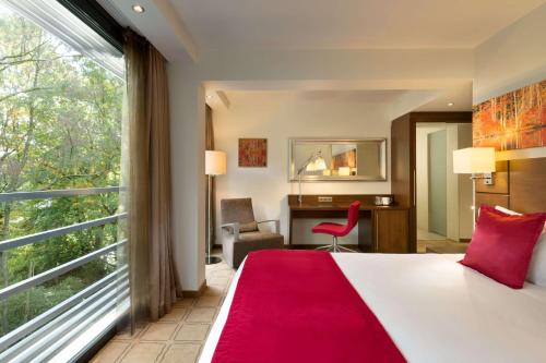 a hotel room with a bed and a large window at Hotel Dolce La Hulpe Brussels in La Hulpe