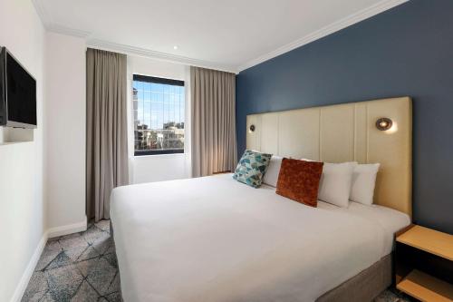 a bedroom with a large white bed and a window at Club Wyndham Sydney, Trademark Collection by Wyndham in Sydney