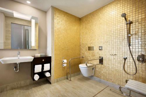 a bathroom with a shower and a toilet and a sink at Ramada By Wyndham Iskenderun in İskenderun