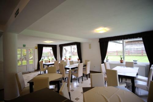 a dining room with tables and chairs and windows at Pensiunea Padurea Verde in Moieciu de Sus