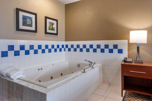 y baño con bañera y azulejos azules y blancos. en Comfort Inn & Suites Napoleon, en Napoleon