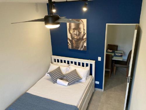 a bedroom with a blue wall and a bed with pillows at Fb HOME Guaruja- Apartamento proximo as praias da Enseada e Pitangueiras - WI FI in Guarujá
