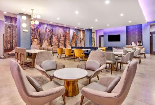 a waiting room with tables and chairs and a tv at La Quinta Inn & Suites by Wyndham Terrell in Terrell