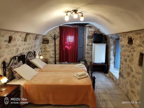 1 dormitorio con 2 camas y cortina roja en Petrounis Hotel, en Areopoli