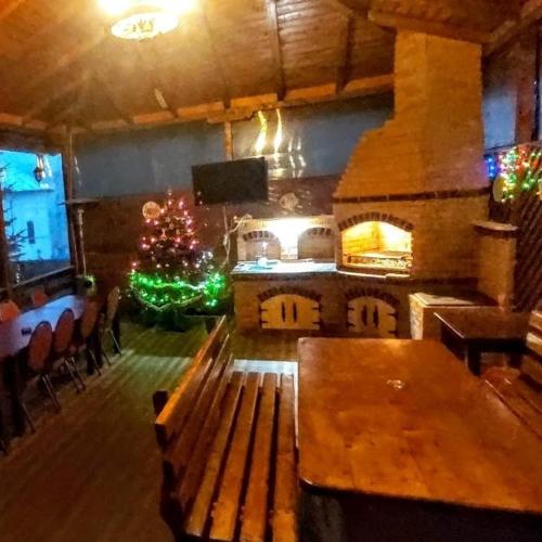 a room with a fireplace and a bench and a christmas tree at Pensiunea Agroturistică Piscul Soarelui in Cîmpulung