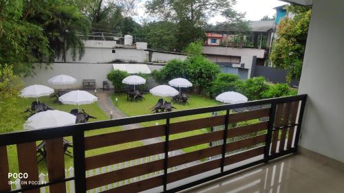a balcony with tables and white umbrellas at Emperor-Hotel Rachana Continental Pvt Ltd in Kizhake Chālakudi