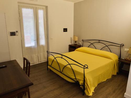 ein Schlafzimmer mit einem gelben Bett, einem Tisch und einem Fenster in der Unterkunft Loggia Piani Nuovi in Carasco