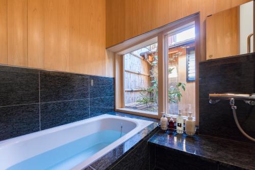 La salle de bains est pourvue d'une baignoire et d'une fenêtre. dans l'établissement Kyomachiya Suite Rikyu, à Kyoto