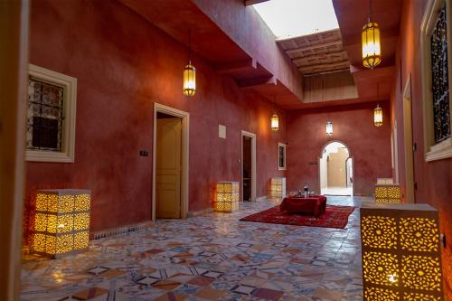 a large room with red walls and a lobby with a couch at Dar Oussidi in Merzouga