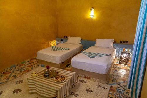 um quarto com duas camas e uma mesa em Dar Oussidi em Merzouga