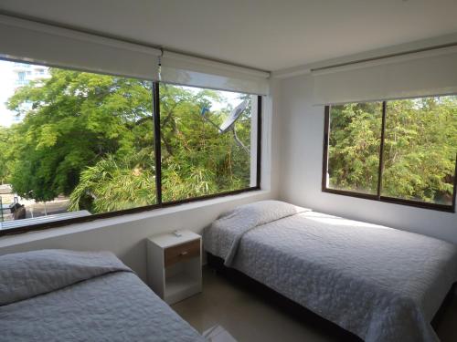 two beds in a bedroom with two windows at Puesta del sol in Santa Marta
