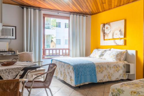 a bedroom with a bed and a table and a dining room at Pousada Residencial dos Corais in Bombinhas