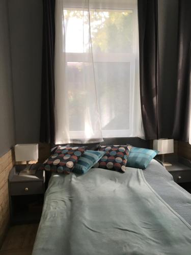 1 cama con 2 almohadas frente a una ventana en Régimódi Apartman, en Siófok